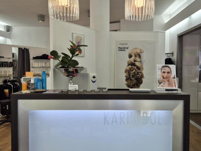 Eingangsbereich des Salons. Blick auf die Theke. Darüber hängen zwei große Lampenschirme.