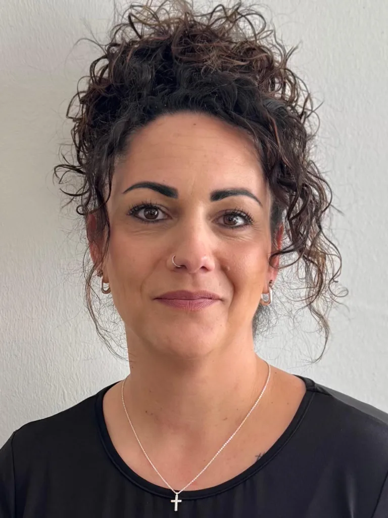 Porträt von Melisa. Sie hat braunes, lockiges Haar.